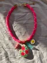 Collar rosado con dije grande con estampado floral y dijes pequeños con forma de huevo frito, pez y caramelo.