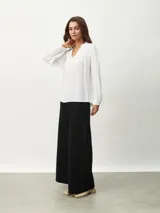 Blusa celeste con cuello mao y escote en V, de mangas largas con puños elásticos.