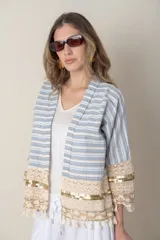 Chaqueta corta de jean rayada en tonos celeste y blanco, con apliques de puntilla y flecos en ruedo y mangas.