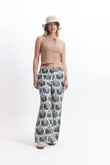 Pantalón wide leg estampado con diseño de conchas marinas color marrón sobre fondo blanco.