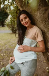 Remera de maternidad color beige con mangas cortas y corte holgado. Presenta un panel horizontal a rayas grises y un sistema de apertura horizontal con telas cruzadas por debajo.