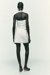 Falda pantalón negra de tiro alto con delantero cruzado y pliegues. Cierre trasero con cremallera oculta.