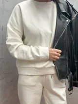 Sudadera color crema de corte holgado, con cuello redondo y mangas largas.