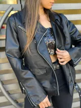 Chaqueta negra estilo motociclista de cuero sintético con cierre asimétrico y cuello con solapas.