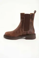 Bota tipo Chelsea de cuero legítimo en color marrón con acabado texturizado. Presenta paneles elásticos laterales al tono, tirador trasero para facilitar el calce y suela de goma gruesa con vira pespunteada.