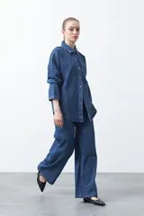 Jean wide leg de color negro con silueta amplia y caída fluida. Presenta detalles de tachas aplicadas que recorren el diseño en forma de ondas. Confeccionado en denim de algodón.