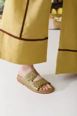 Sandalias bajas color verde oliva con dos tiras con borde festoneado y tachas doradas.