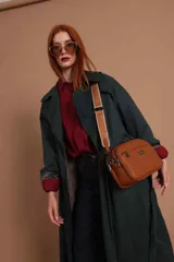 Bandolera color mostaza de simil cuero, con tres cierres principales, cierre delantero y bolsillo trasero. Incluye correa ajustable.