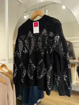 Sweater tejido negro con cuello redondo y mangas largas. Presenta un patrón de rombos con lentejuelas plateadas.