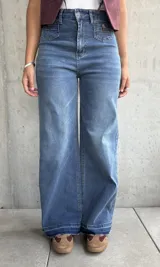 Jean de mujer color azul claro, de corte recto y tiro alto, con bolsillos delanteros decorativos con solapa y botón.