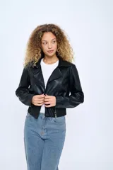 Campera corta de cuero sintético negro, estilo motoquero, con cuello clásico, cierre asimétrico con cremallera, bolsillos laterales con cremallera y puños con cremallera.