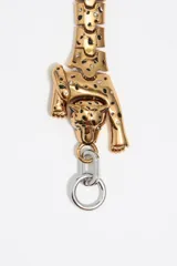 Pulsera dorada con eslabones articulados formando el cuerpo de un leopardo. Cierre con barra en forma de T plateada.