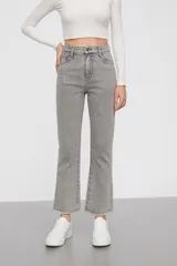 Pantalón jean gris de tiro alto, corte flare cropped y ruedo desflecado.