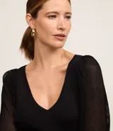 Blusa negra de punto con escote en V y mangas largas abullonadas con detalles de encaje.
