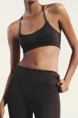 Top negro con escote redondo, tirantes finos ajustables y tejido combinado en tul a tono. Cierre en espalda con gancho metálico.