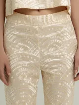 Pantalón negro con estampado dorado de motivos geométricos, corte flare y tiro alto.