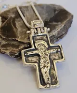 Collar con dije de cruz plateada con la figura de Cristo en relieve.