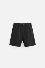 Bermuda negra regular fit confeccionada en tejido con mezcla de algodón y lino. Cintura elástica ajustable con cordón. Pliegues frontales. Bolsillos laterales y traseros de vivo. Cierre frontal con cremallera y botón.
