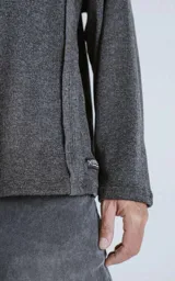Sweater gris oscuro de manga larga con cuello redondo y paneles laterales con costuras a la vista.