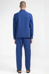 Chaqueta azul con textura seersucker, cuello con solapa, cierre con botones, bolsillo en el pecho y dos bolsillos de parche redondeados.