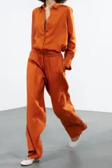 Pantalón palazzo color ladrillo confeccionado en lino 100%, de tiro medio con cintura ajustable con cordones, bolsillos laterales ocultos en costura y pierna ancha.