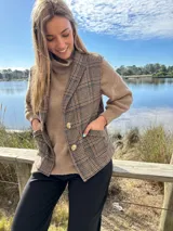 Chaleco marrón a cuadros con botones dorados y bolsillos delanteros.