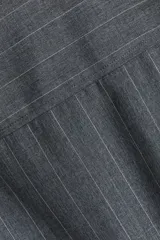 Camisa larga gris con rayas verticales finas, cuello clásico, cierre frontal de botones y mangas largas con puños abotonados.