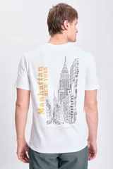Remera blanca de manga corta con estampa en la espalda de la ciudad de Manhattan y texto en color dorado.