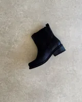 Bota de cuero color marrón con caña alta, hebillas y arnés.