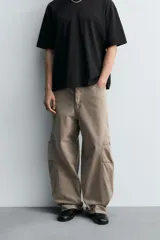 Pantalón de jean color marrón topo, de corte holgado y amplio en toda la pierna, con tiro medio, cinco bolsillos, efecto lavado, detalle de pinzas en perneras y cierre frontal con cremallera y botón.