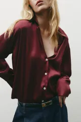 Camisa color borgoña de satén con cuello solapa, escote en pico, manga larga y cierre frontal con botones.