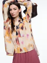 Camisa de manga larga confeccionada en viscosa crinkled con estampa de manchas. De silueta amplia y fluida, con bolsillos frontales grandes, tajos laterales y largo extendido en la espalda.