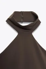 Top celeste de cuello halter y hombros descubiertos, con cierre de botones en la espalda.