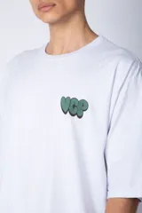 Remera blanca de corte oversize con mangas cortas y cuello redondo. Estampado pequeño en el frente con letras verdes.