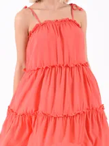Vestido corto color naranja oscuro, con breteles finos y volados en el escote y en los cortes de la falda.
