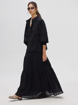 Camisa de broderie de algodón color negro, con cuello mao y cierre de cuatro botones. Presenta mangas abullonadas y galones con transparencias en la parte delantera y mangas.