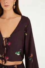 Blusa corta color marrón con estampado de cócteles, escote en V con lazo, mangas largas acampanadas y corte holgado.