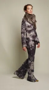 Pantalón de tiro medio con elástico en la cintura y corte acampanado. Diseño con estampado abstracto en tonos marrones, rojizos y amarillos, con textura tipo piel de reptil.