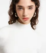 Vestido de punto blanco, manga larga, con cuello alto y corte evasé.