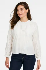 Blusa blanca de algodón con cuello alto con detalles de encaje, mangas largas abullonadas con puños elásticos y bordados calados.