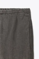 Pantalón de lino gris con cintura ajustable con cordones y bolsillos laterales ocultos.