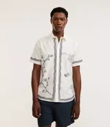 Camisa de manga corta confeccionada en algodón y lino, color blanco con bordado floral en negro.