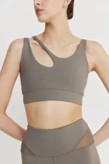 Top deportivo asimétrico color gris topo, con bretel asimétrico y abertura en el frente.