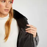 Campera puffer gris de franela con cuello de piel sintética negra, cierre frontal con cremallera dorada y bolsillos laterales.