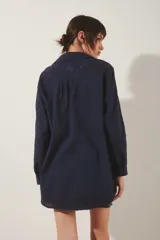 Camisa blanca de algodón con fit amplio, cuello y cartera frontal, y bordados calados en el frente, mangas y espalda. Posee tajos laterales y presillas internas para regular el largo de las mangas.