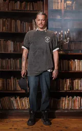 Remera gris con efecto lavado, de corte oversize y manga corta. Estampado frontal con diseño de estilo tarot con estrellas, figuras femeninas y plantas.