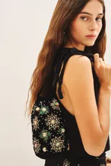 Cartera tipo tote bag de terciopelo negro con bordados de flores y estrellas de lentejuelas y mostacillas de colores. Tiene doble asa de cordón trenzado negro con cuentas en los extremos.