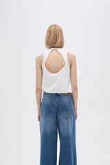 Blusa blanca de algodón sin mangas, con cuello a la base, abertura en la espalda y lazo ajustable.