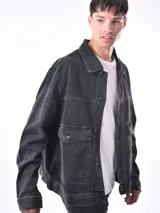 Campera de jean negra con cuello clásico, cierre frontal con botones metálicos, bolsillos con solapa en el pecho y corte recto.