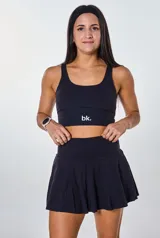 Conjunto deportivo negro compuesto por un top con logo "bk." y una falda corta con short interno.
